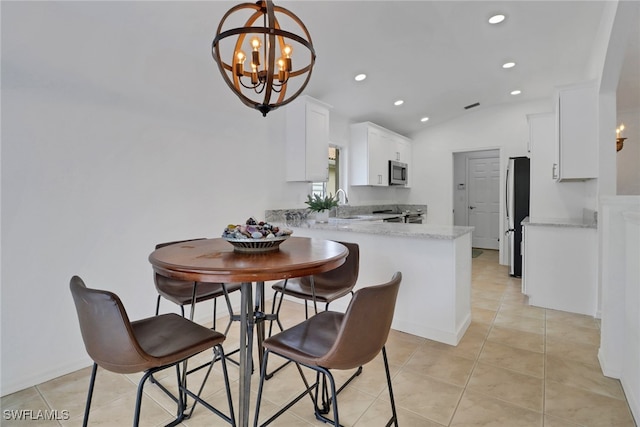 tiled dining space with vaulted ceiling, sink, and a notable chandelier