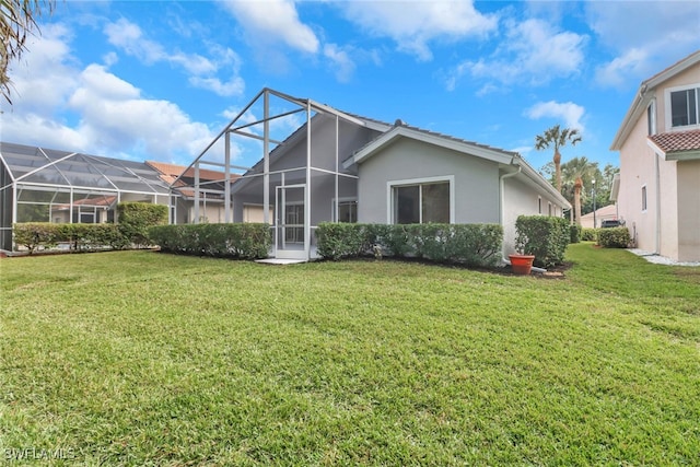 rear view of house featuring a lanai and a lawn