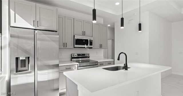 kitchen featuring gray cabinetry, sink, decorative light fixtures, a center island with sink, and appliances with stainless steel finishes