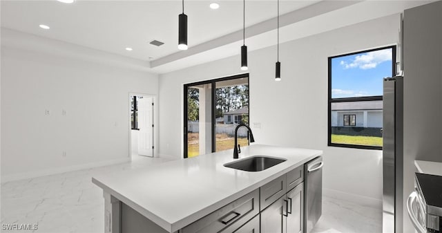 kitchen featuring pendant lighting, gray cabinetry, a center island with sink, sink, and stainless steel appliances