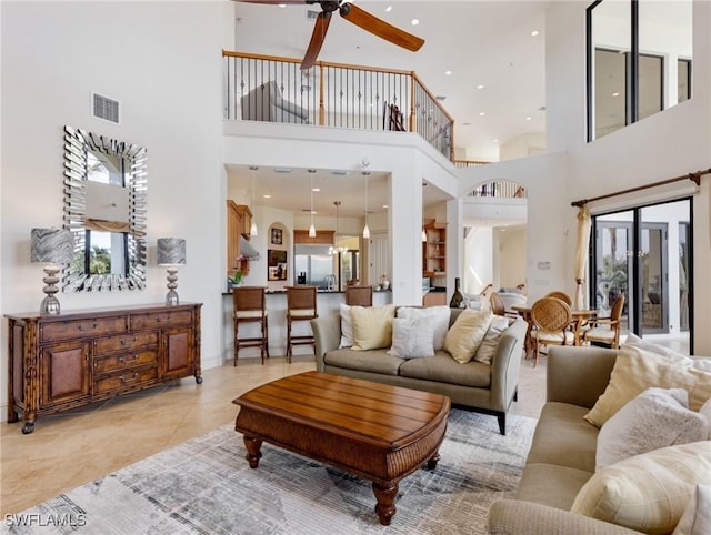 living room with ceiling fan, light tile patterned flooring, and a high ceiling