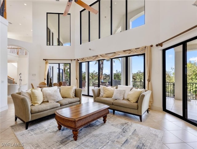 tiled living room featuring ceiling fan and a towering ceiling