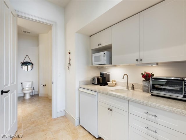 kitchen with light stone counters, sink, white cabinets, and white appliances