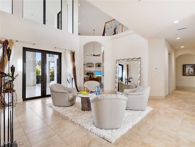 living room with french doors, a towering ceiling, and ceiling fan