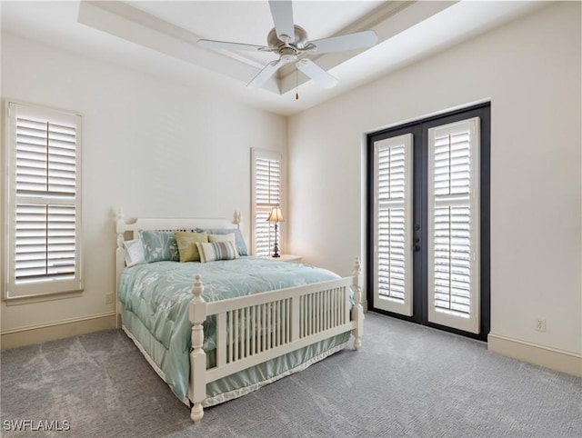 carpeted bedroom with ceiling fan, a raised ceiling, access to outside, and french doors