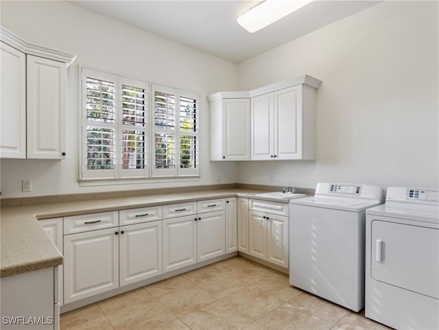 clothes washing area with cabinets, light tile patterned floors, washing machine and dryer, and sink