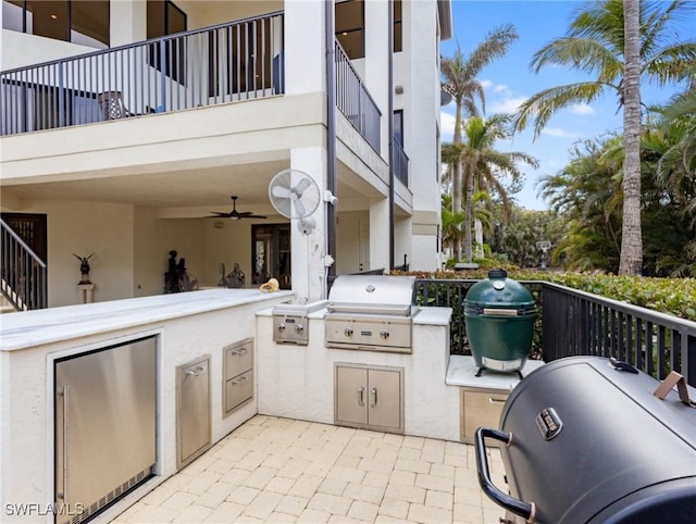 view of patio / terrace featuring grilling area, ceiling fan, a balcony, and exterior kitchen