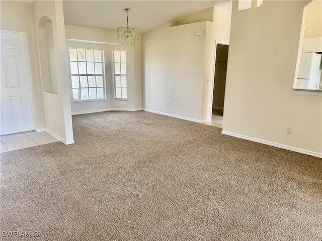 unfurnished room with light colored carpet, vaulted ceiling, and an inviting chandelier