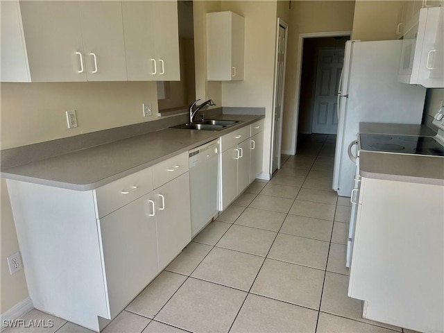 kitchen with stove, white dishwasher, sink, light tile patterned floors, and white cabinets