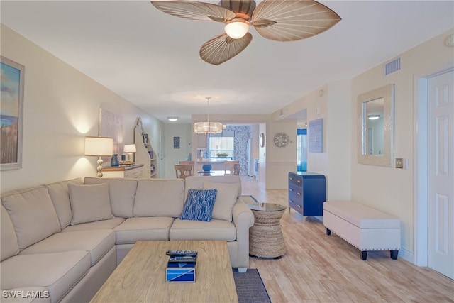 living room featuring light hardwood / wood-style flooring and ceiling fan with notable chandelier