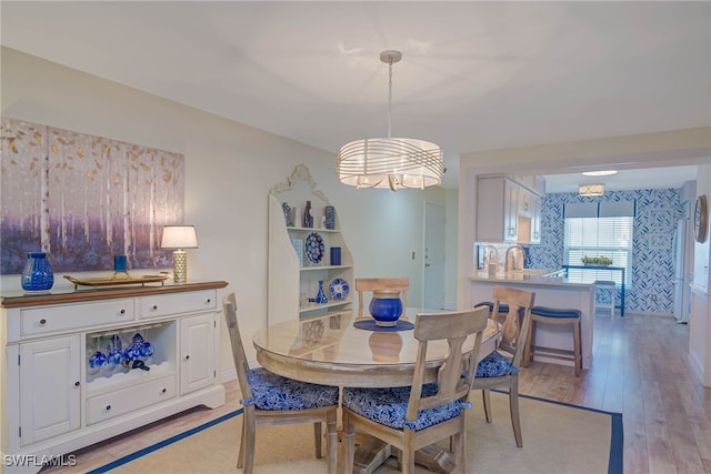 dining area featuring light wood-type flooring, sink, and a chandelier