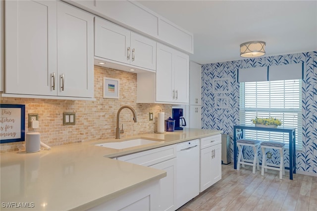 kitchen with tasteful backsplash, sink, light hardwood / wood-style flooring, dishwasher, and white cabinetry