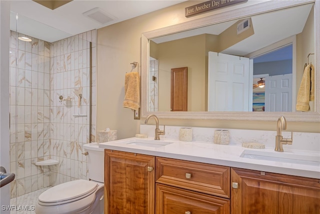 bathroom featuring a tile shower, vanity, toilet, and ceiling fan