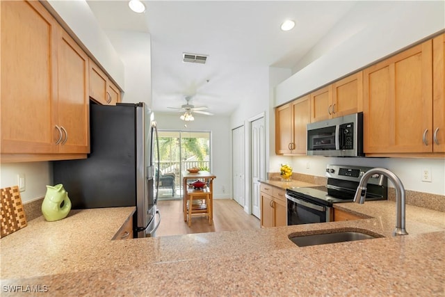 kitchen featuring lofted ceiling, sink, ceiling fan, stainless steel appliances, and light stone countertops