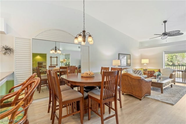 dining room with ceiling fan with notable chandelier, vaulted ceiling, and light hardwood / wood-style floors