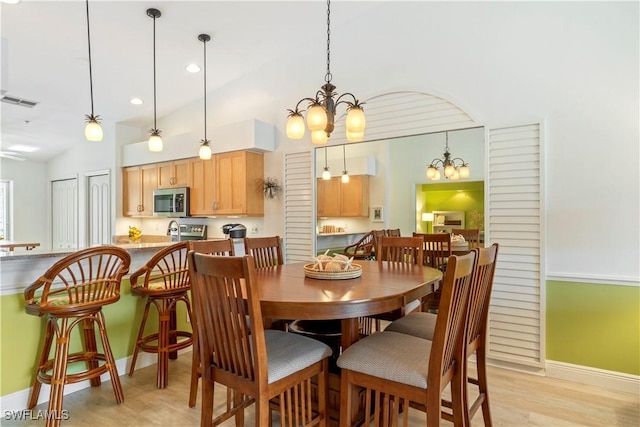 dining room with lofted ceiling, light wood-type flooring, and a chandelier