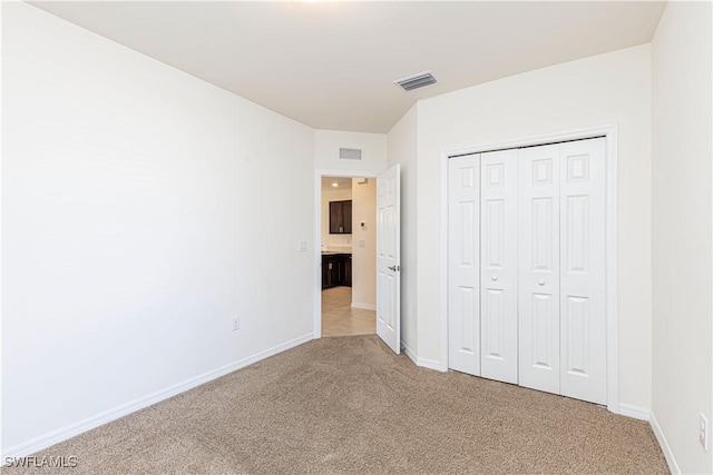 unfurnished bedroom with light colored carpet and a closet