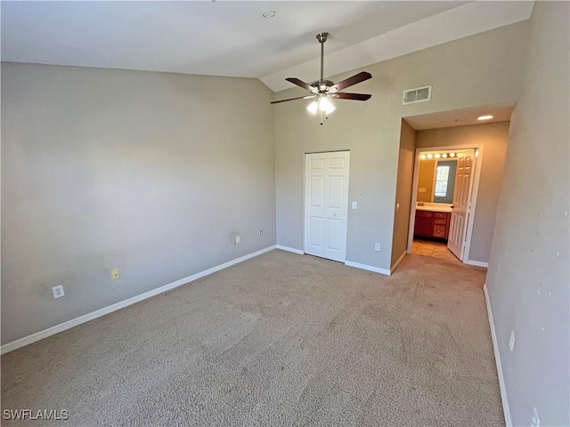 unfurnished bedroom featuring ensuite bathroom, ceiling fan, lofted ceiling, and light colored carpet