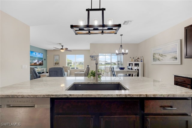 kitchen featuring light stone countertops, dark brown cabinets, ceiling fan with notable chandelier, pendant lighting, and dishwasher