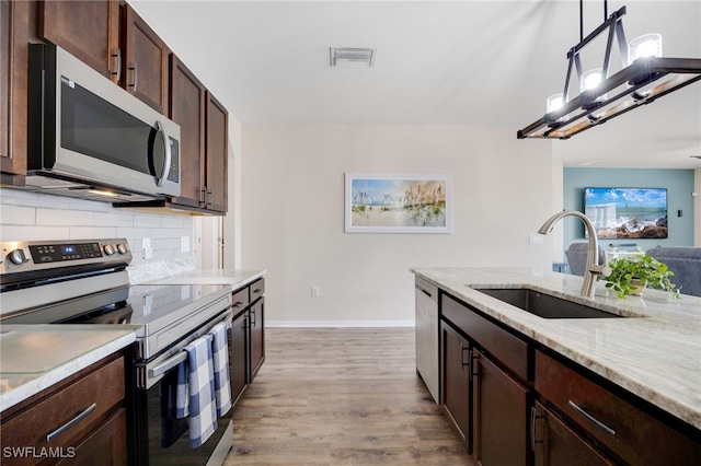 kitchen with sink, hanging light fixtures, light hardwood / wood-style flooring, backsplash, and appliances with stainless steel finishes