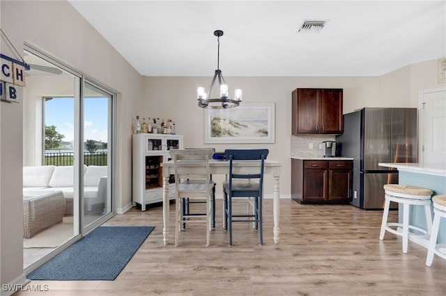 kitchen featuring decorative backsplash, stainless steel fridge, light hardwood / wood-style flooring, and pendant lighting