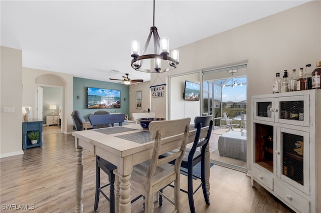 dining area with wood-type flooring and ceiling fan with notable chandelier