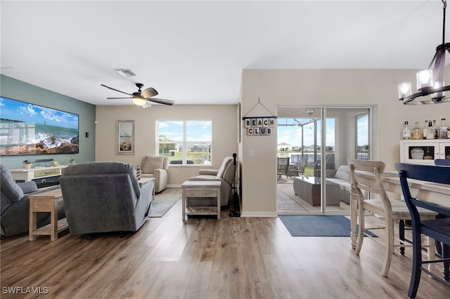 living room with ceiling fan with notable chandelier and hardwood / wood-style flooring