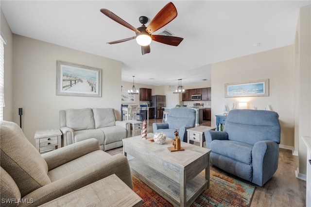 living room featuring ceiling fan with notable chandelier and hardwood / wood-style flooring