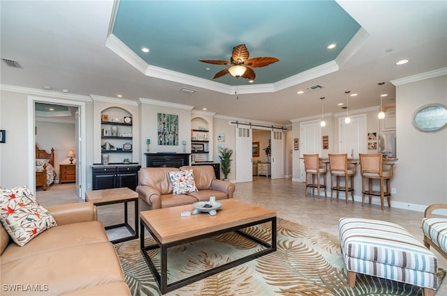 living room featuring a raised ceiling, built in shelves, ceiling fan, and a barn door