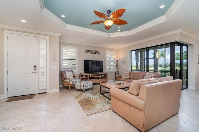 tiled living room with ceiling fan, crown molding, and a tray ceiling