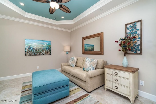 living room with a raised ceiling, ceiling fan, and ornamental molding