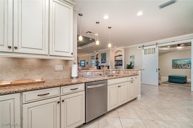 kitchen with light stone counters, sink, a barn door, decorative light fixtures, and dishwasher