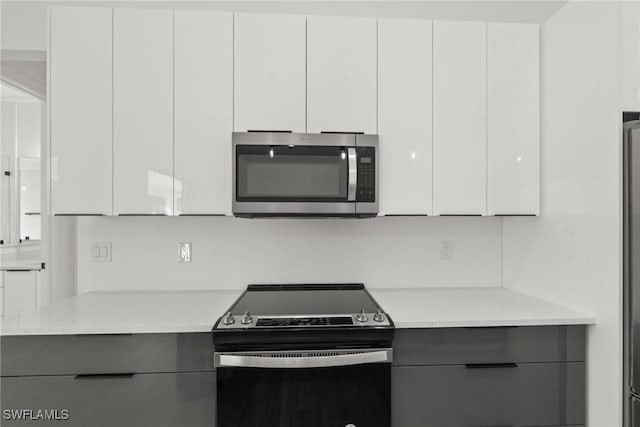 kitchen featuring light stone countertops, white cabinetry, and stainless steel appliances