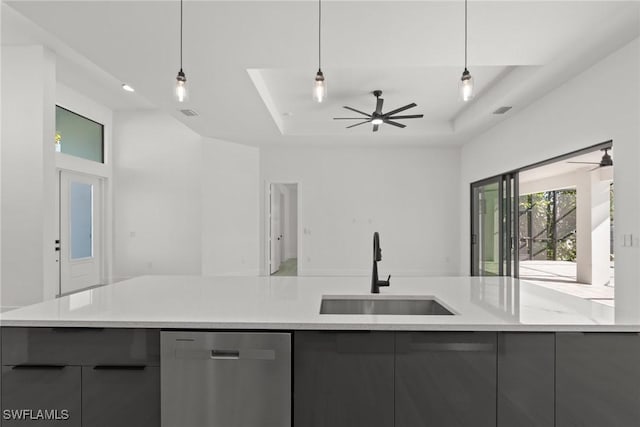 kitchen with a raised ceiling, sink, stainless steel dishwasher, and decorative light fixtures