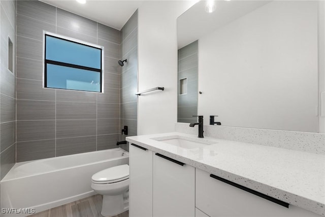 full bathroom with vanity, hardwood / wood-style floors, tiled shower / bath, and toilet