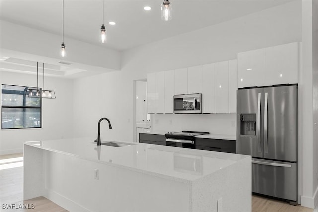 kitchen with a kitchen island with sink, white cabinets, decorative light fixtures, and appliances with stainless steel finishes