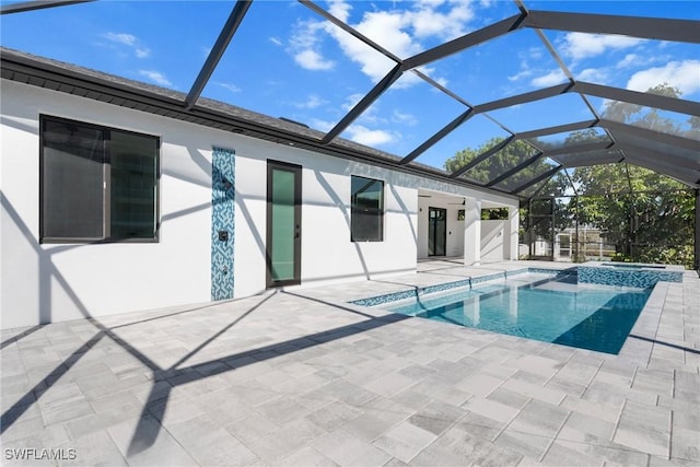 view of pool with glass enclosure, an in ground hot tub, and a patio