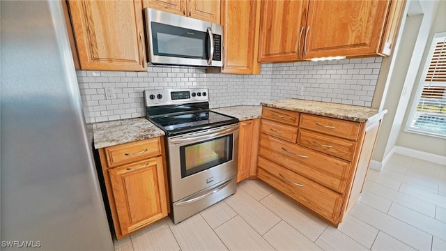 kitchen featuring stainless steel appliances, decorative backsplash, light tile patterned floors, and light stone countertops