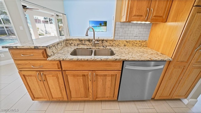 kitchen featuring dishwasher, ceiling fan, light stone counters, decorative backsplash, and sink