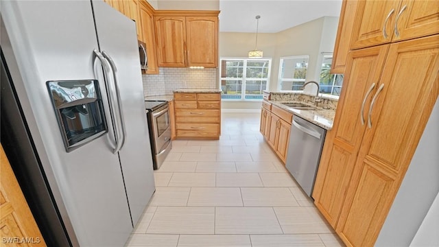 kitchen with stainless steel appliances, hanging light fixtures, light stone countertops, sink, and backsplash