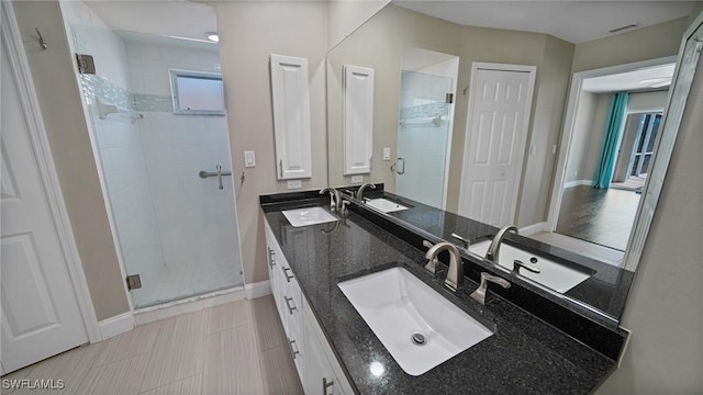 bathroom featuring a shower with door and vanity