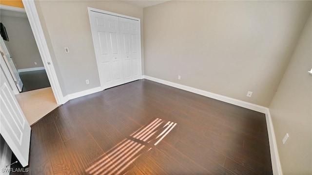 unfurnished bedroom featuring a closet and dark hardwood / wood-style floors