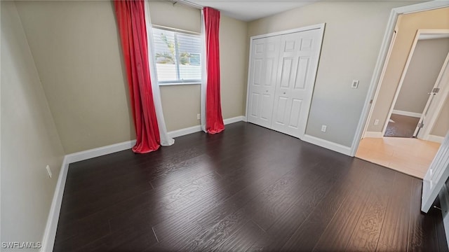 unfurnished bedroom featuring a closet and dark hardwood / wood-style floors