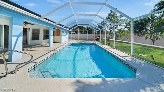 view of pool featuring a yard, ceiling fan, glass enclosure, and a patio