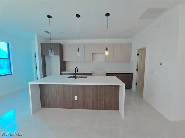 kitchen featuring decorative light fixtures, white cabinetry, and an island with sink