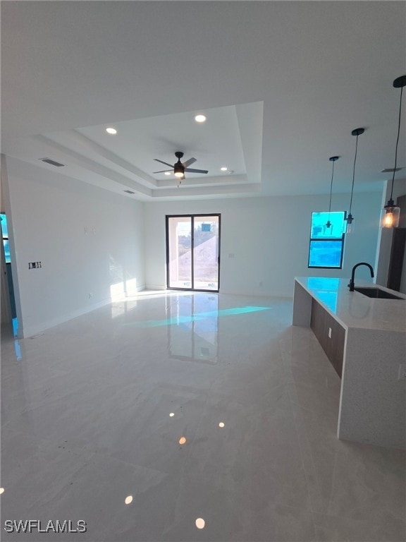 interior space featuring ceiling fan, sink, and a tray ceiling