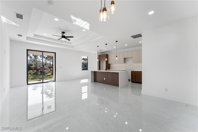 unfurnished living room with sink, a tray ceiling, and ceiling fan