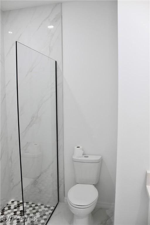 bathroom featuring marble finish floor, a marble finish shower, and toilet