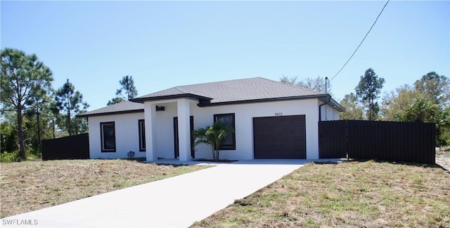 view of front facade with concrete driveway, an attached garage, fence, and stucco siding