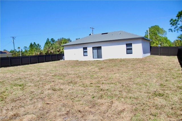 rear view of house featuring a fenced backyard and a lawn